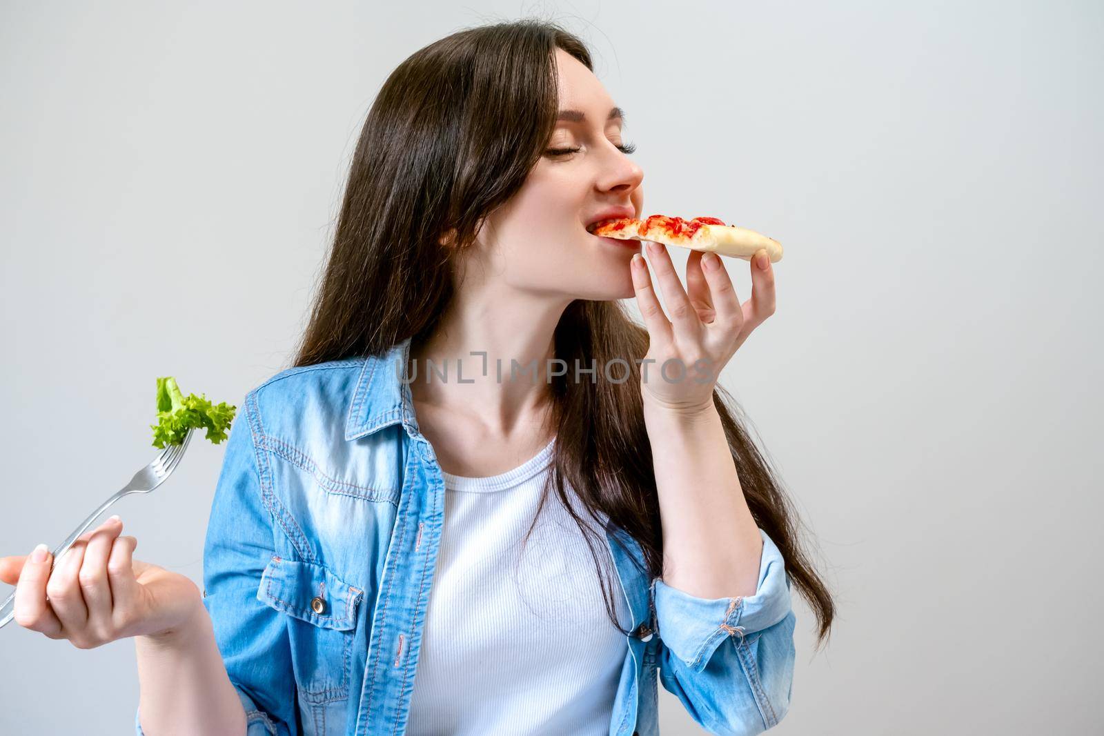 Young beautiful woman breaks the diet, but happy eats pizza instead of salad.