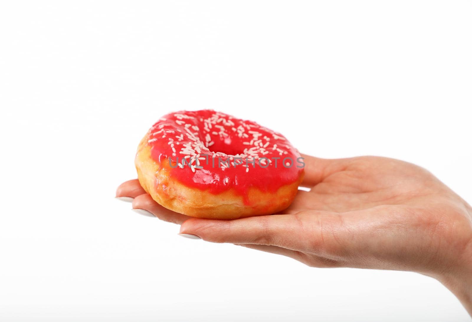 Close up Caucasian woman hand holding one red icing glazed ring doughnut isolated on white background, symbol of unhealthy eating concept, low angle, side view