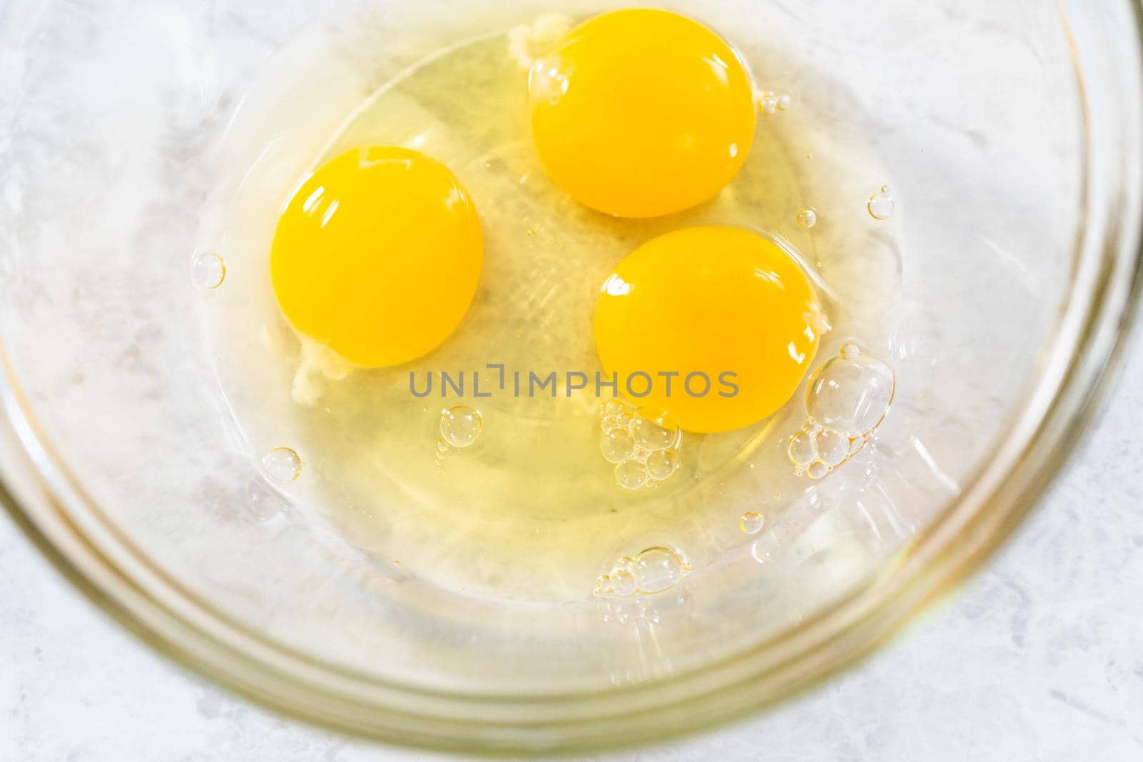 Mixing ingredients in a glass mixing bowl to bake funfettti bundt cake.
