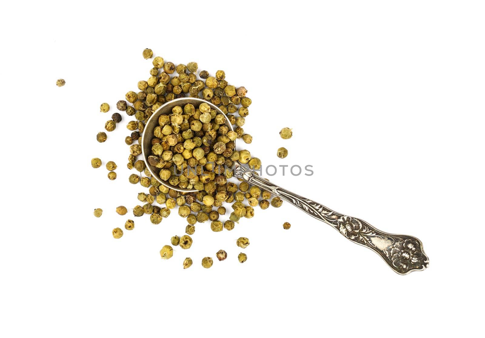 Close up one vintage metal spoon full of green pepper peppercorns and heap of peppercorns spilled and spread around isolated on white background, elevated top view, directly above