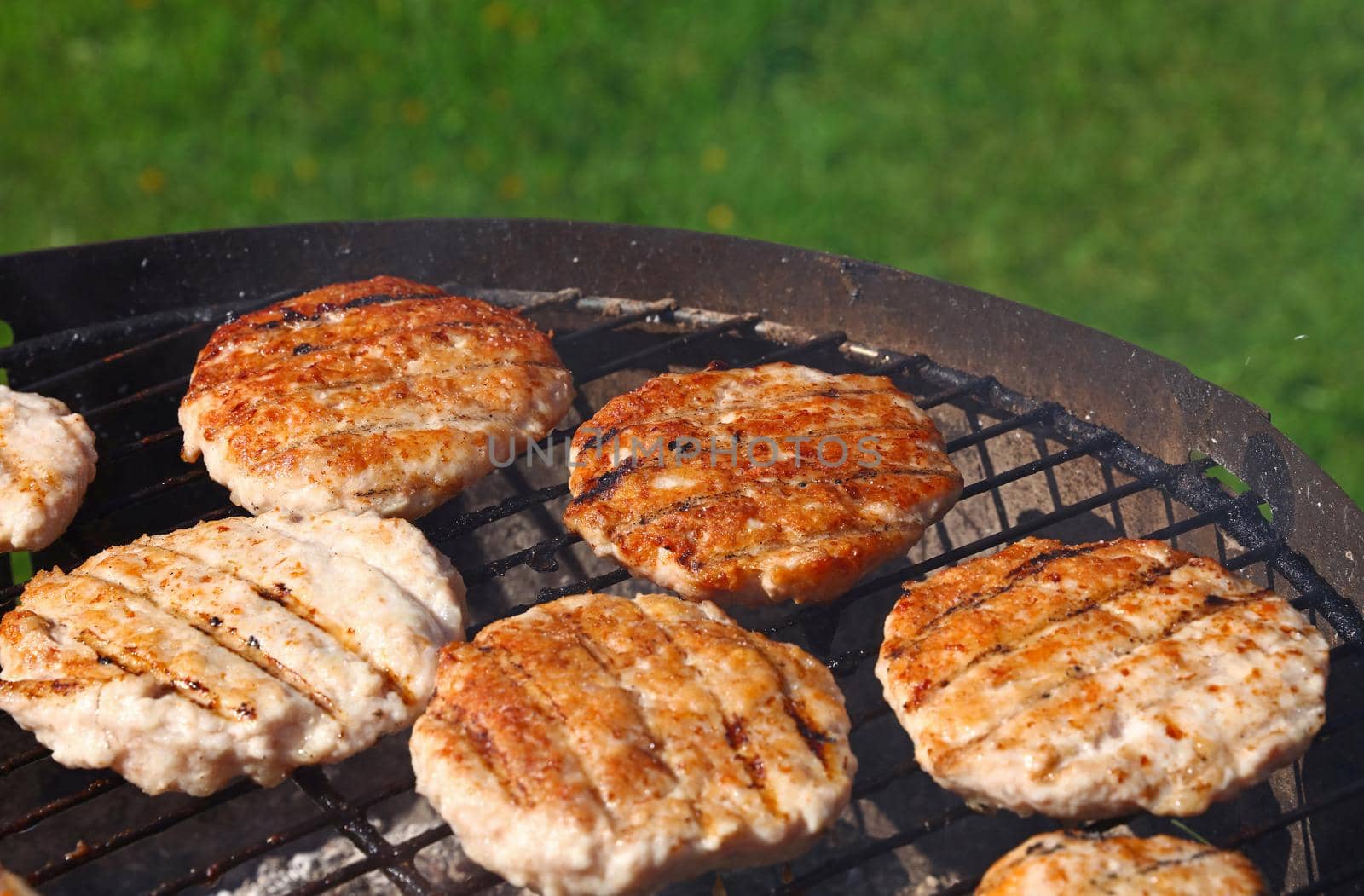 Close up chicken or turkey poultry meat barbecue burgers for hamburgers prepared on bbq grill, high angle view