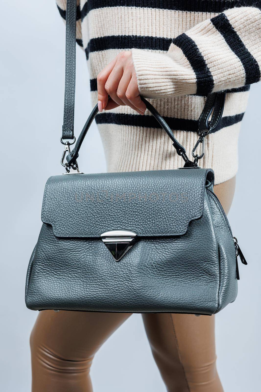 Woman with a gray leather bag on a white background. Stylish clutch bag. Close-up vertical photo.