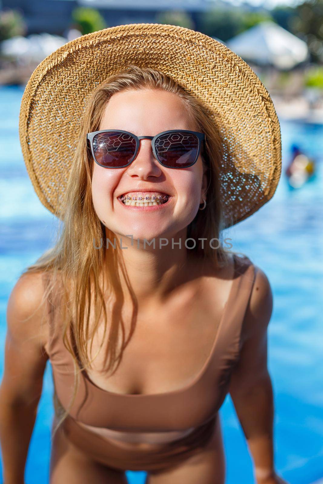 Slender woman model in a swimsuit posing near the pool. Summer vacation at the hotel,