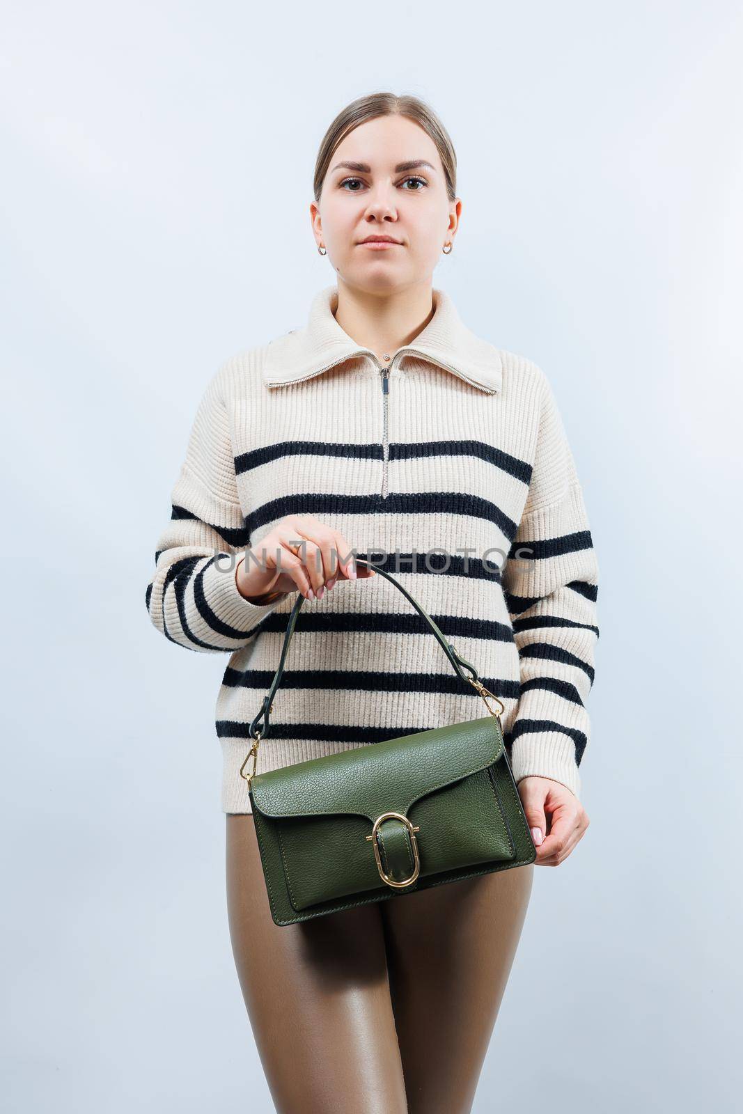 Small green leather bag in a female hand on a white background. Shoulder bag. A woman with a green handbag. Style, fashion, vintage and elegance.