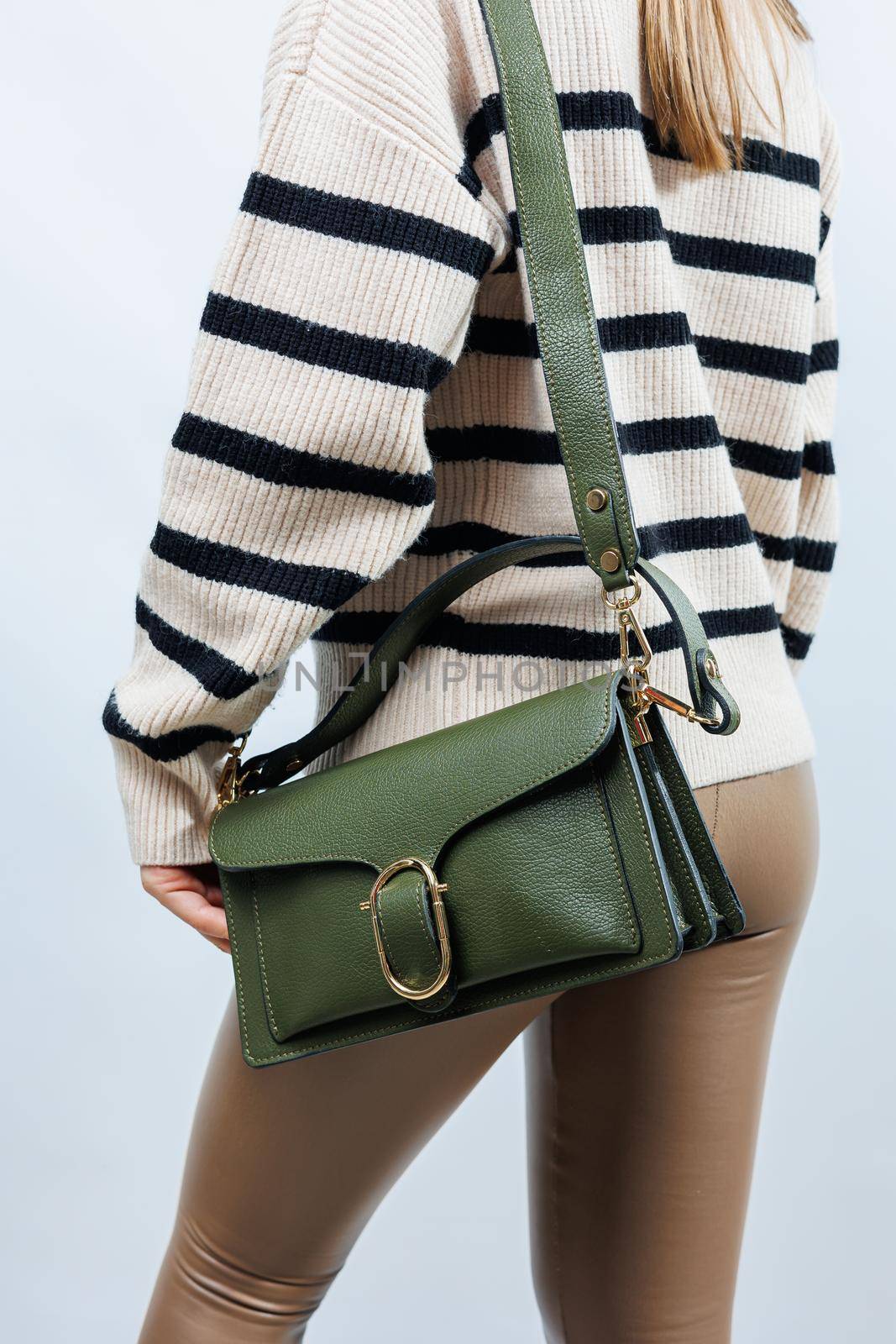 Small green leather bag in a female hand on a white background. Shoulder bag. A woman with a green handbag. Style, fashion, vintage and elegance.