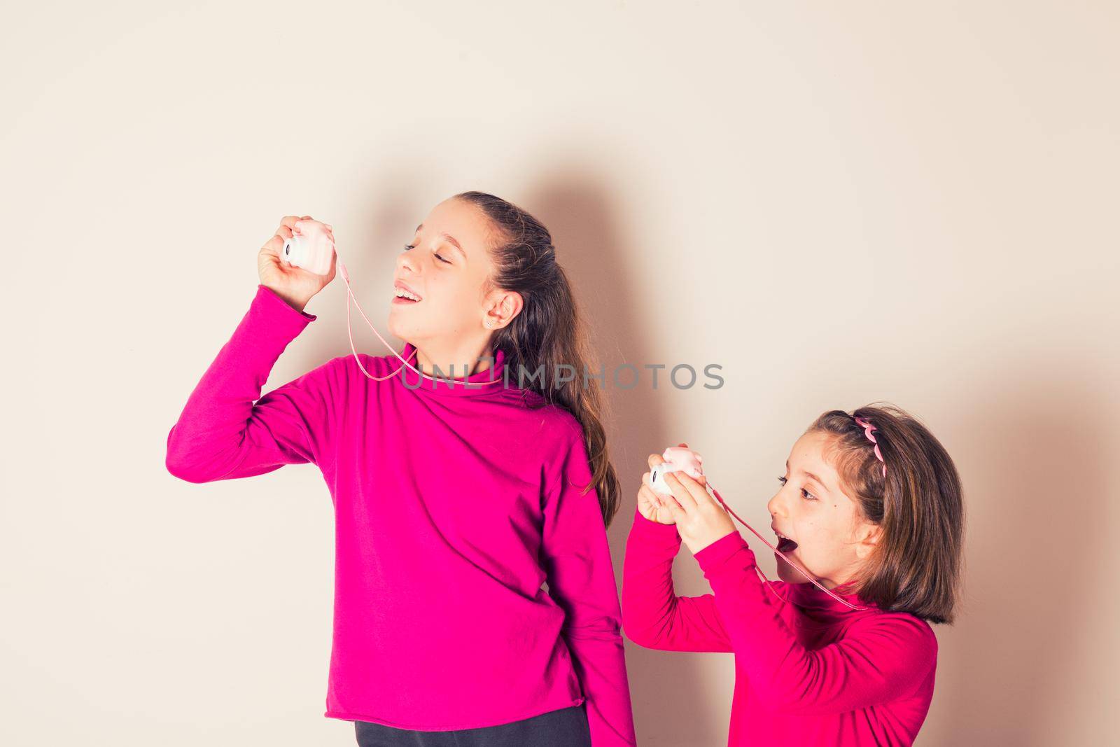 Couple of Little Girls Taking Picture Using Toy Photo Camera on white background by bepsimage