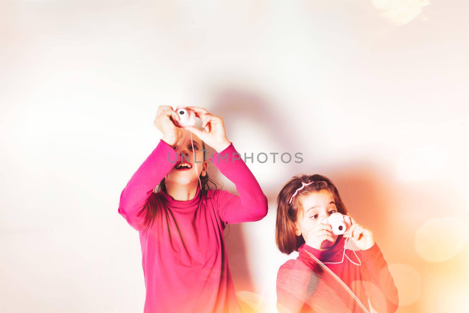 Couple of Little Girls Taking Picture Using Toy Photo Camera on white background. High quality photo