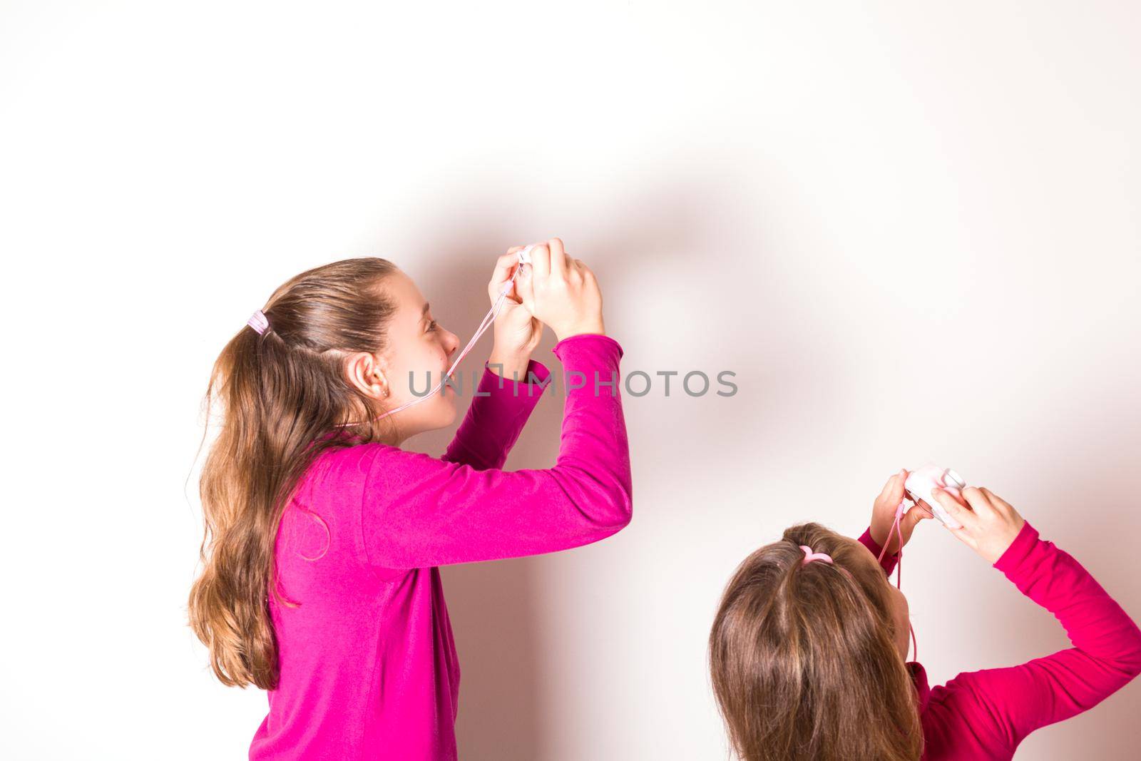 Couple of Little Girls Taking Picture Using Toy Photo Camera on white background. High quality photo