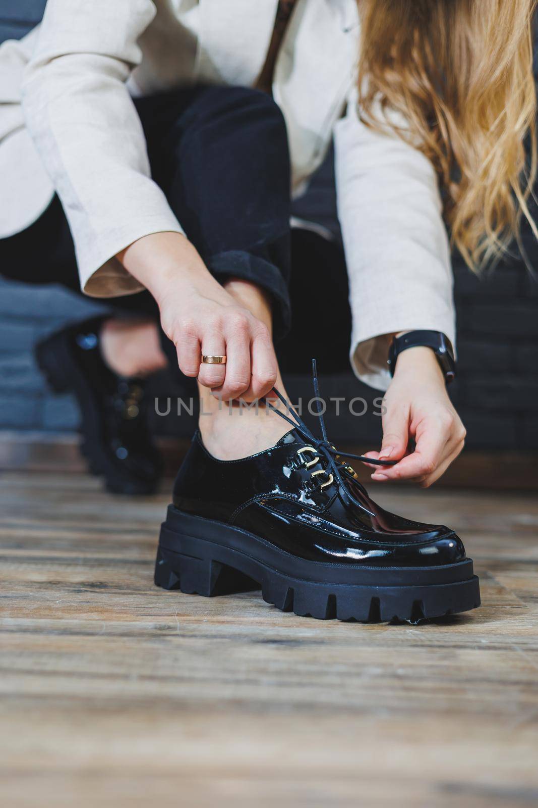 Beautiful woman with legs in fashionable clothes, stylish leather black patent leather lace-up shoes close-up. Women's image in spring style