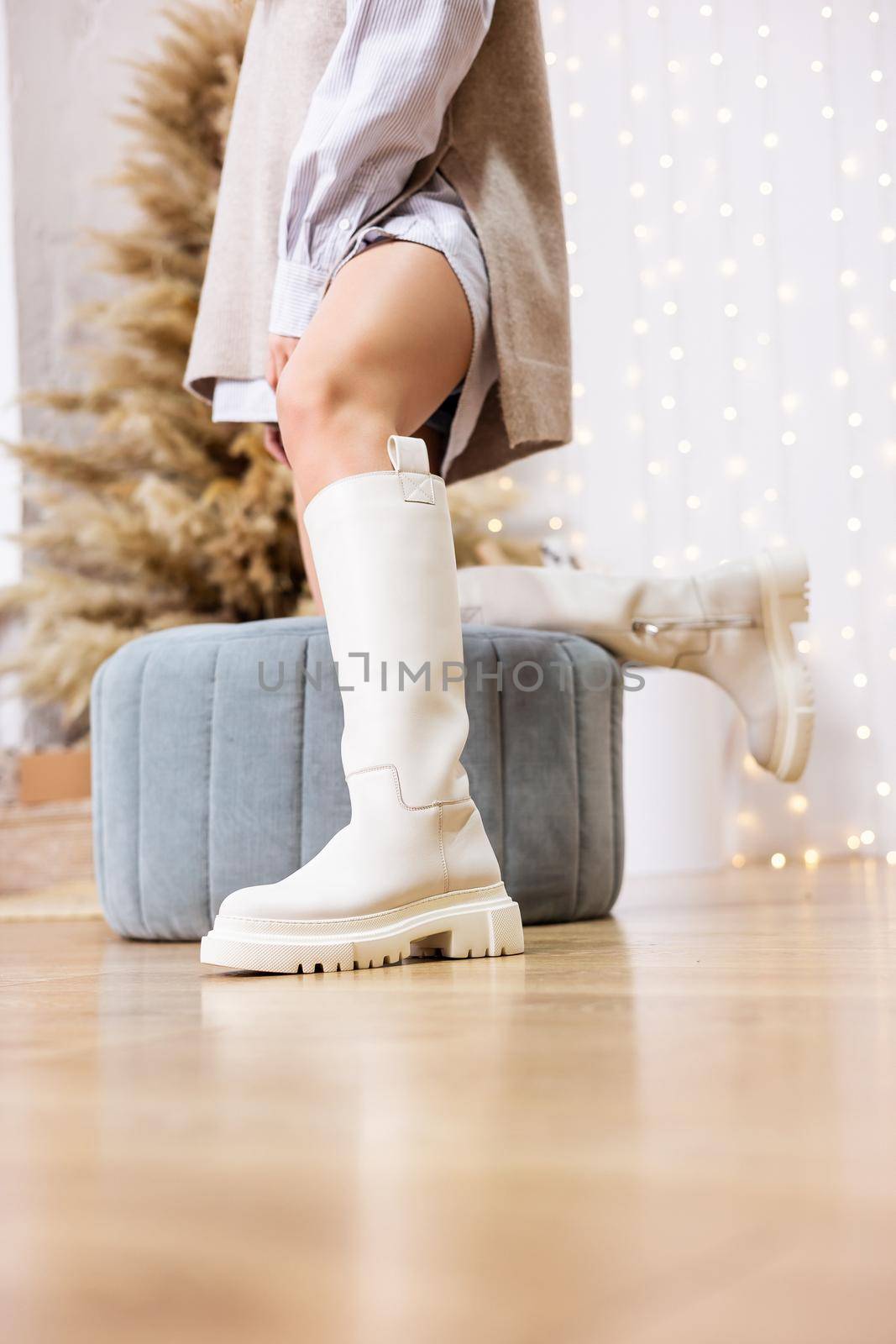 Trendy beige trumpet boots on a female leg, close-up, fashionable. New collection of women's shoes with genuine leather