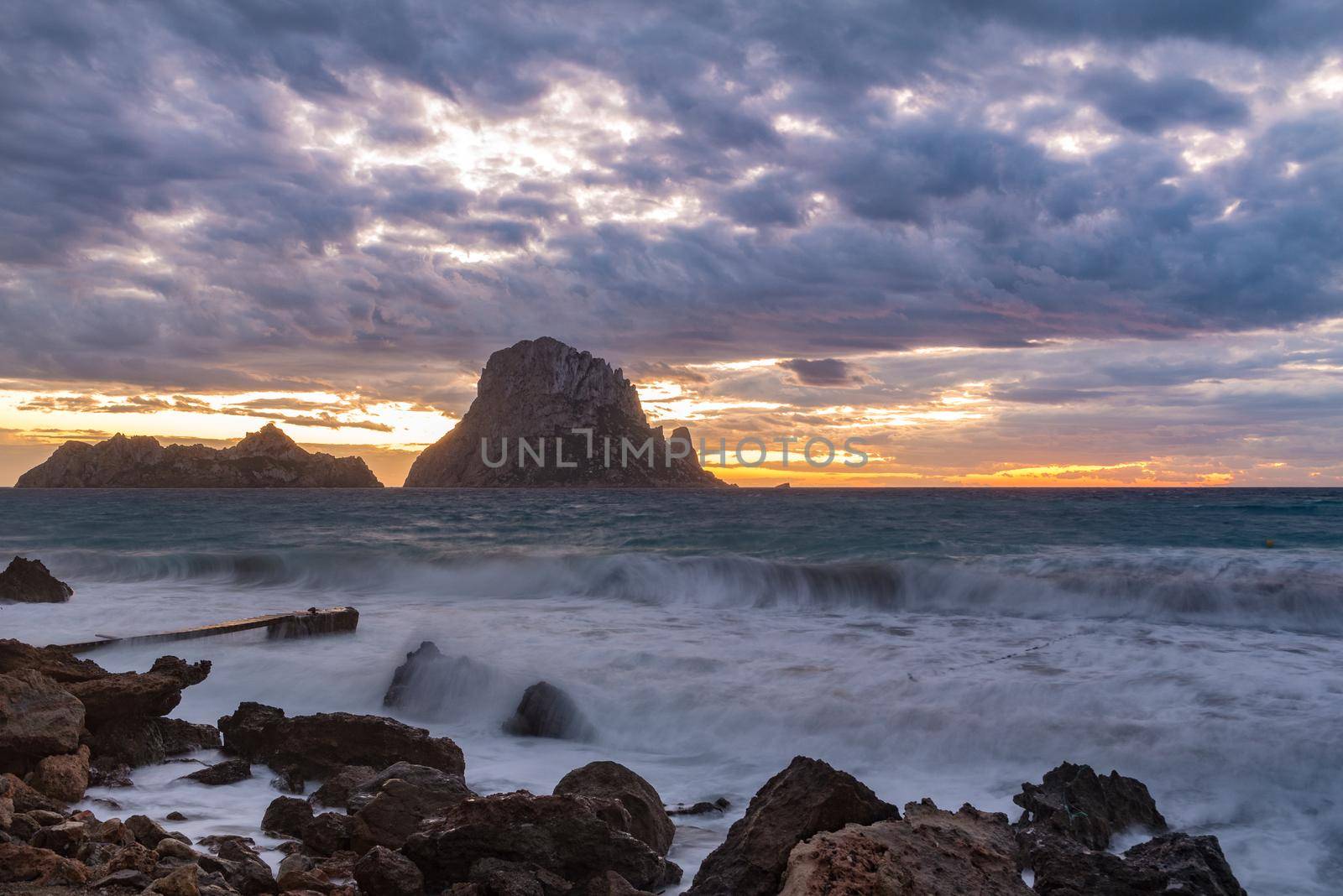 Small wooden pier in Cala d'Hort bay and view of Es Vedra island, Ibiza island, Spain