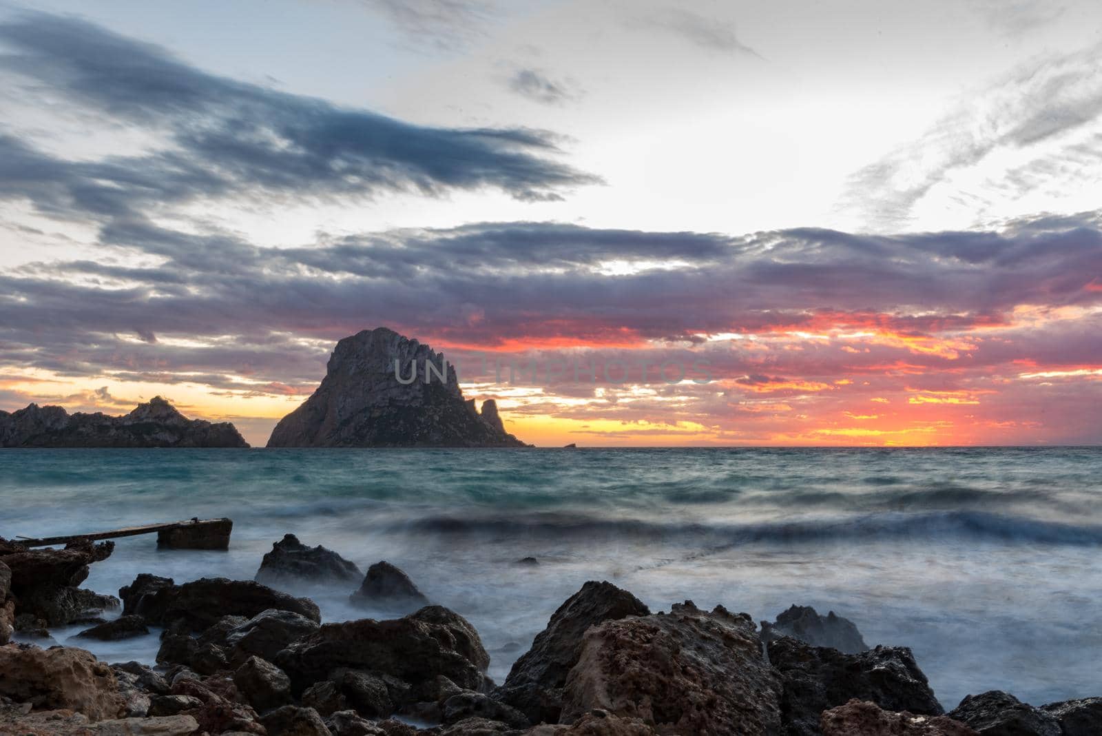 Small wooden pier in Cala d'Hort bay and view of Es Vedra island, Ibiza island, Spain  by martinscphoto