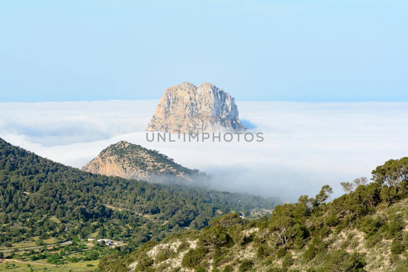 Peak of the mountain is vedra peeping through the fog one autumn morning in Sant Josep de Sa Talaia, Ibiza, Balearic Islands, Spain by martinscphoto