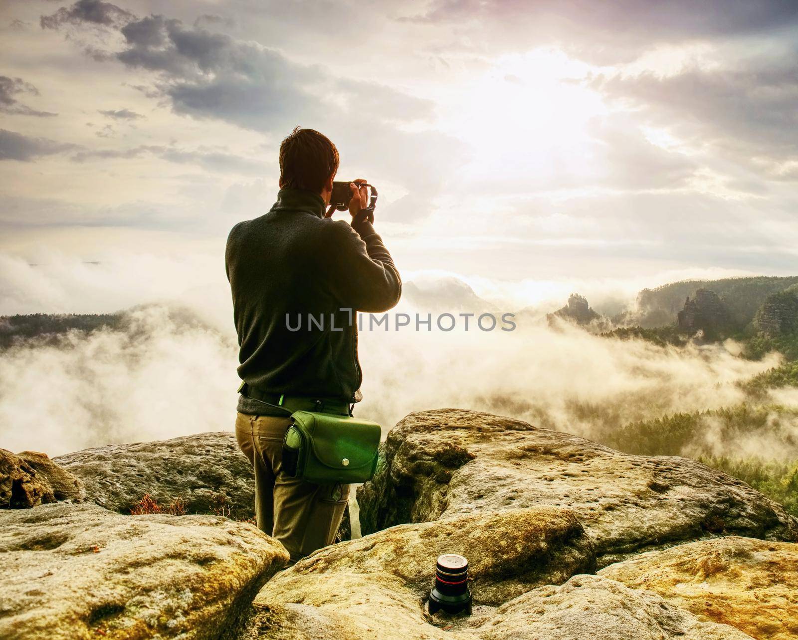 Photographer looks into fall landscape through camera viewfinder. Man prepare camera to takes impressive photos of misty fall mountains.