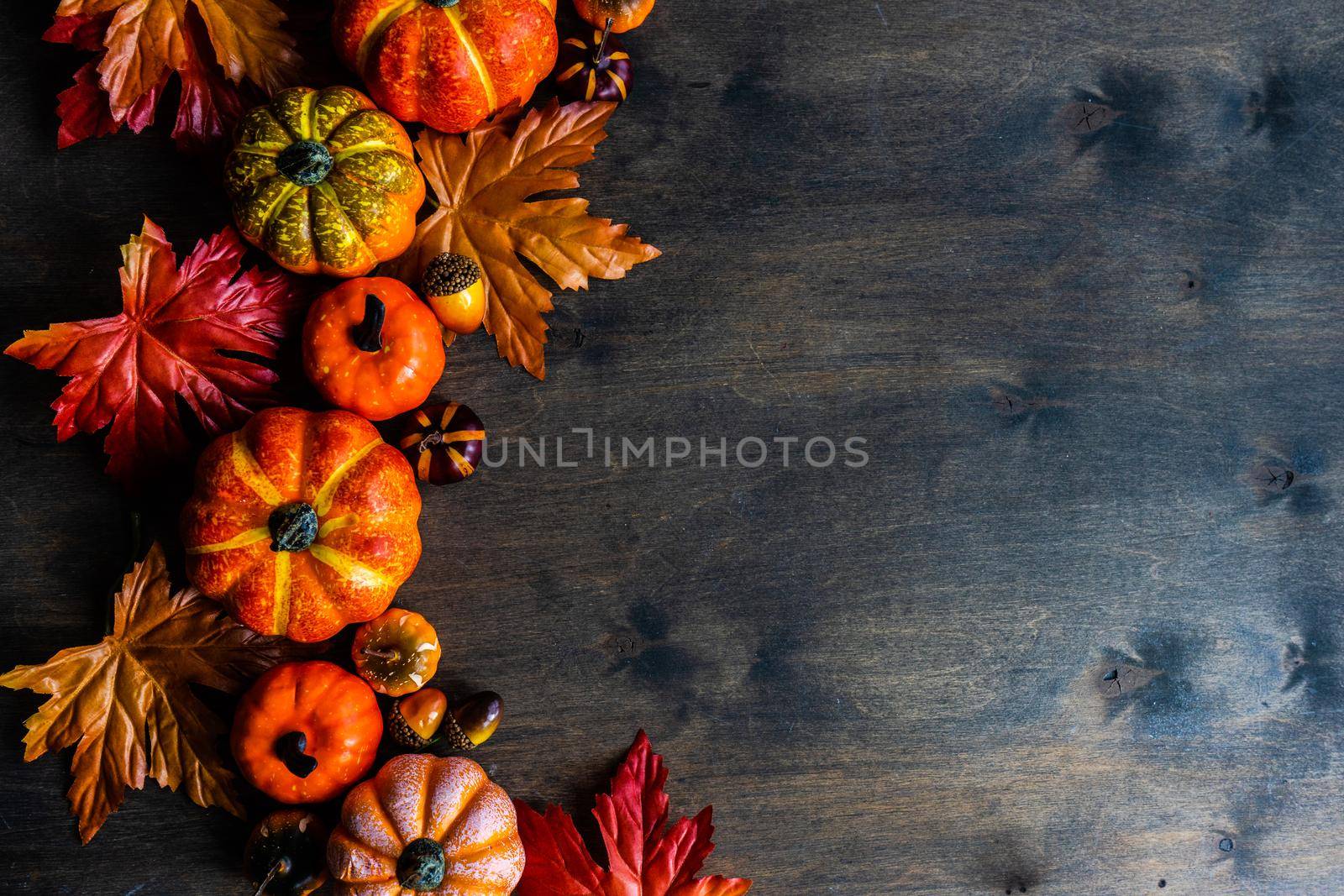 Autumnal flat lay with leaves and pumpkins on wooden background