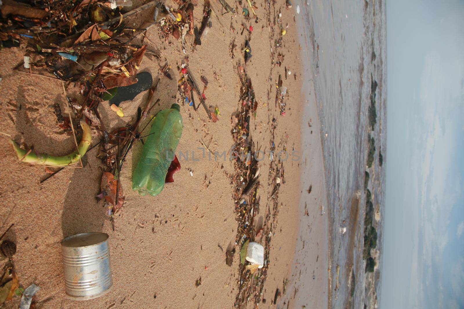 salvador, bahia, brazil - november 30, 2021: Plastic bottle and heaped garbage is seen in the sand of Costa Azul beach near the mouth of Rio Camurigipe in Salvador city.