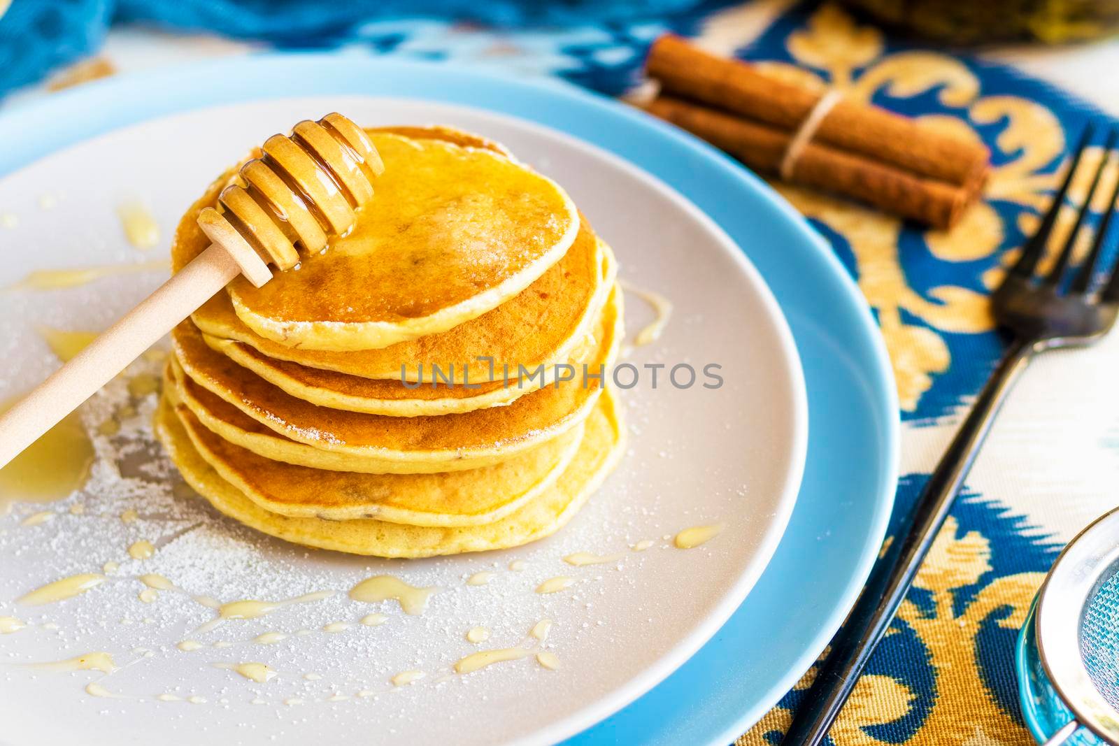 classic american breakfast. homemade banana pancakes on plate sprinkled powder and honey. Pancakes on the kitchen table . Pancake slide with honey topping . High quality photo