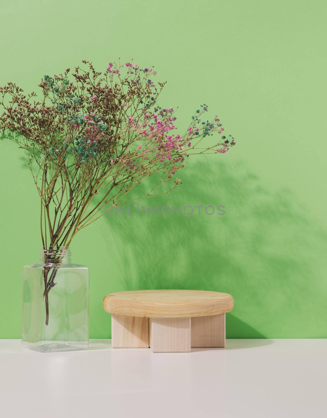 Stage for displaying products, cosmetics with a round wooden podium and a glass vase by ndanko