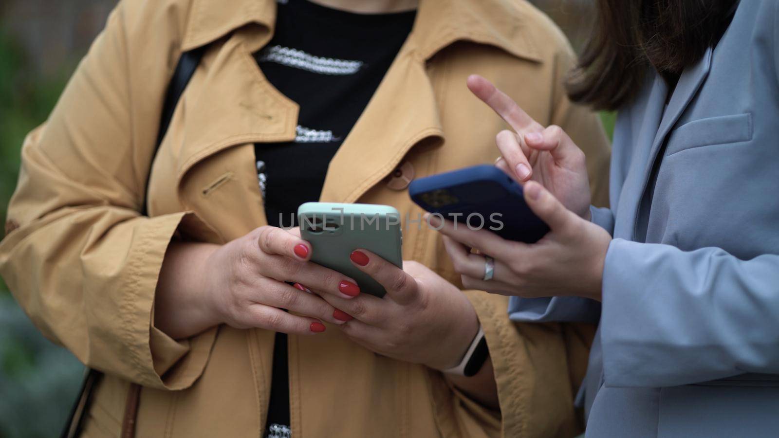 Women's hands hold smartphones. Women communicate and use phones.