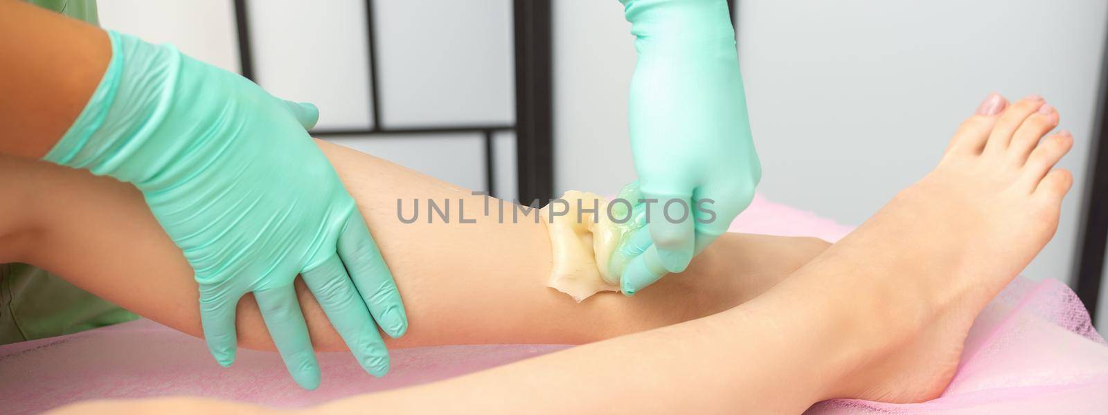 Waxing depilation procedure for removing hair on legs with sugaring paste in the beauty salon. by okskukuruza