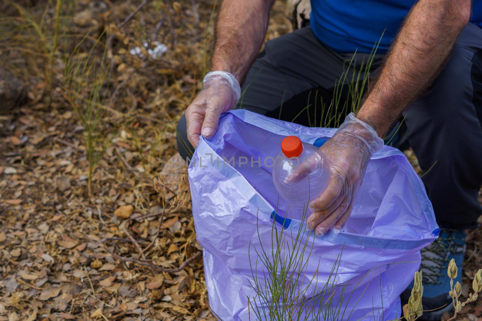 environmentalist man picking up garbage from the field by joseantona