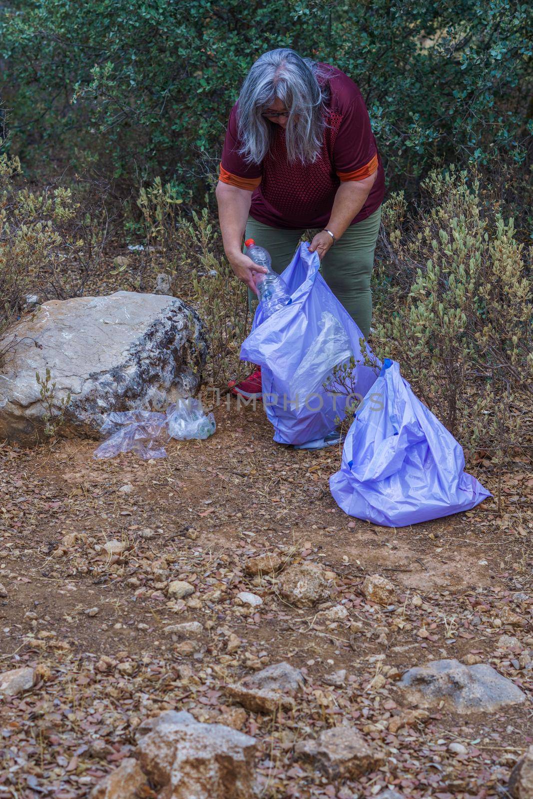 woman ecologist with garbage bags picking up garbage from the field and taking care of the environment