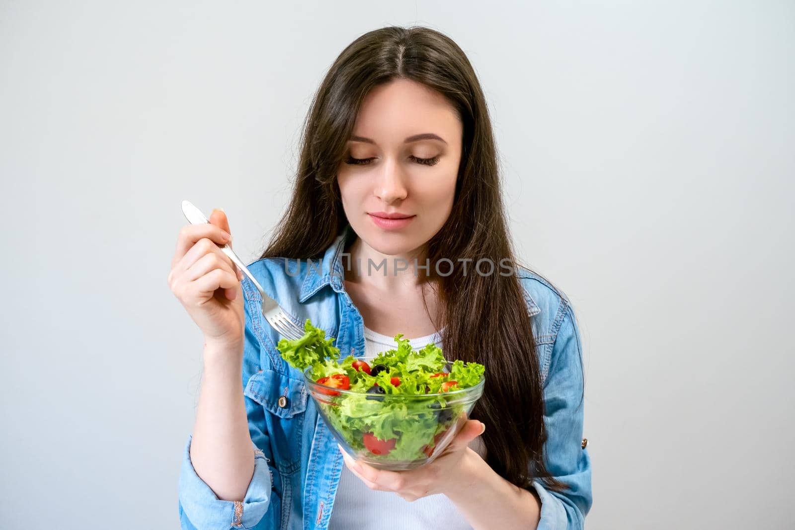 Beautiful young woman eats salad with lettuce, tomato and olives by Svetlana_Belozerova