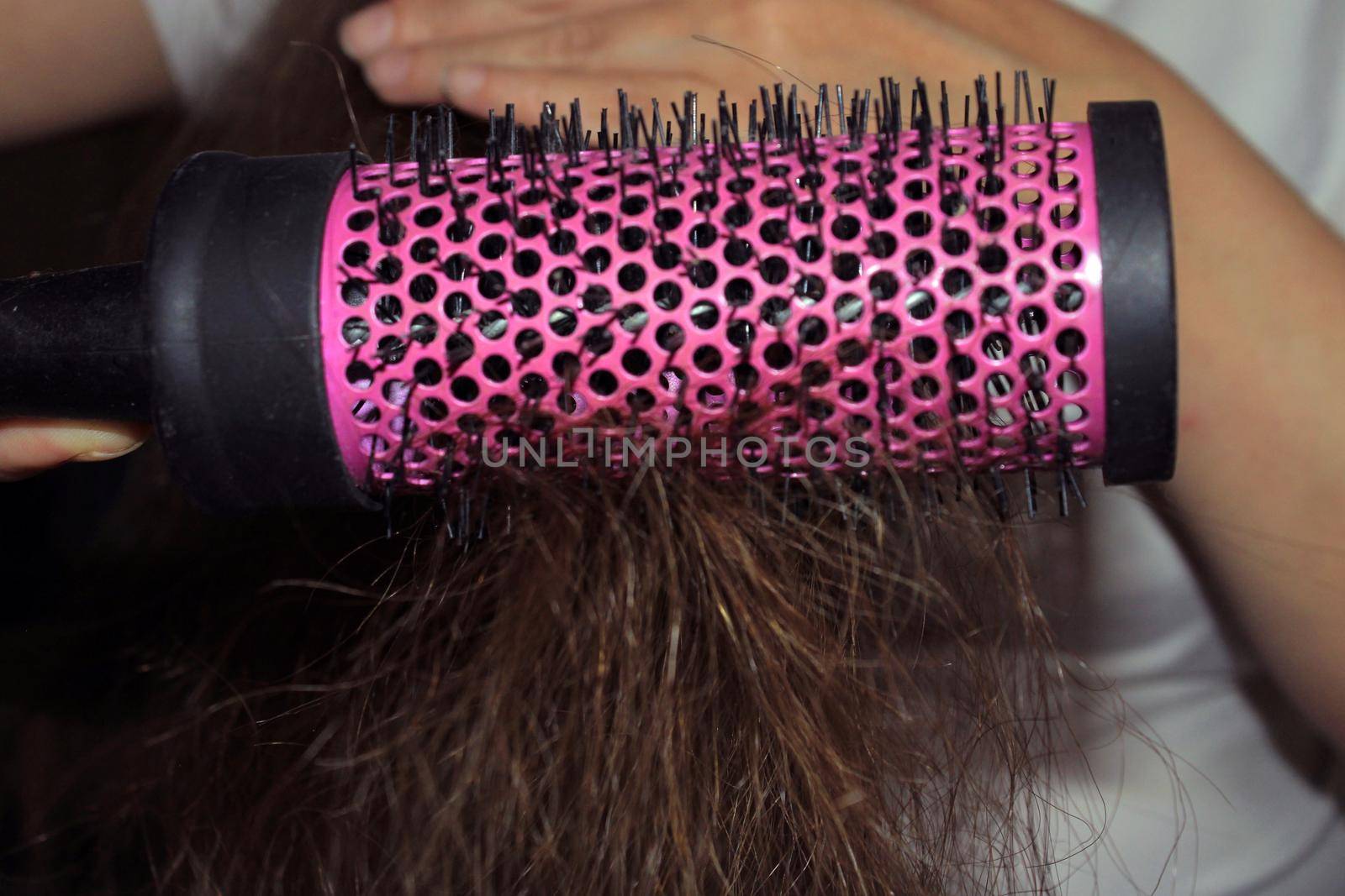 A girl with dark long hair combs her hair. Hairbrush close-up. Hair care. Hair loss problem.