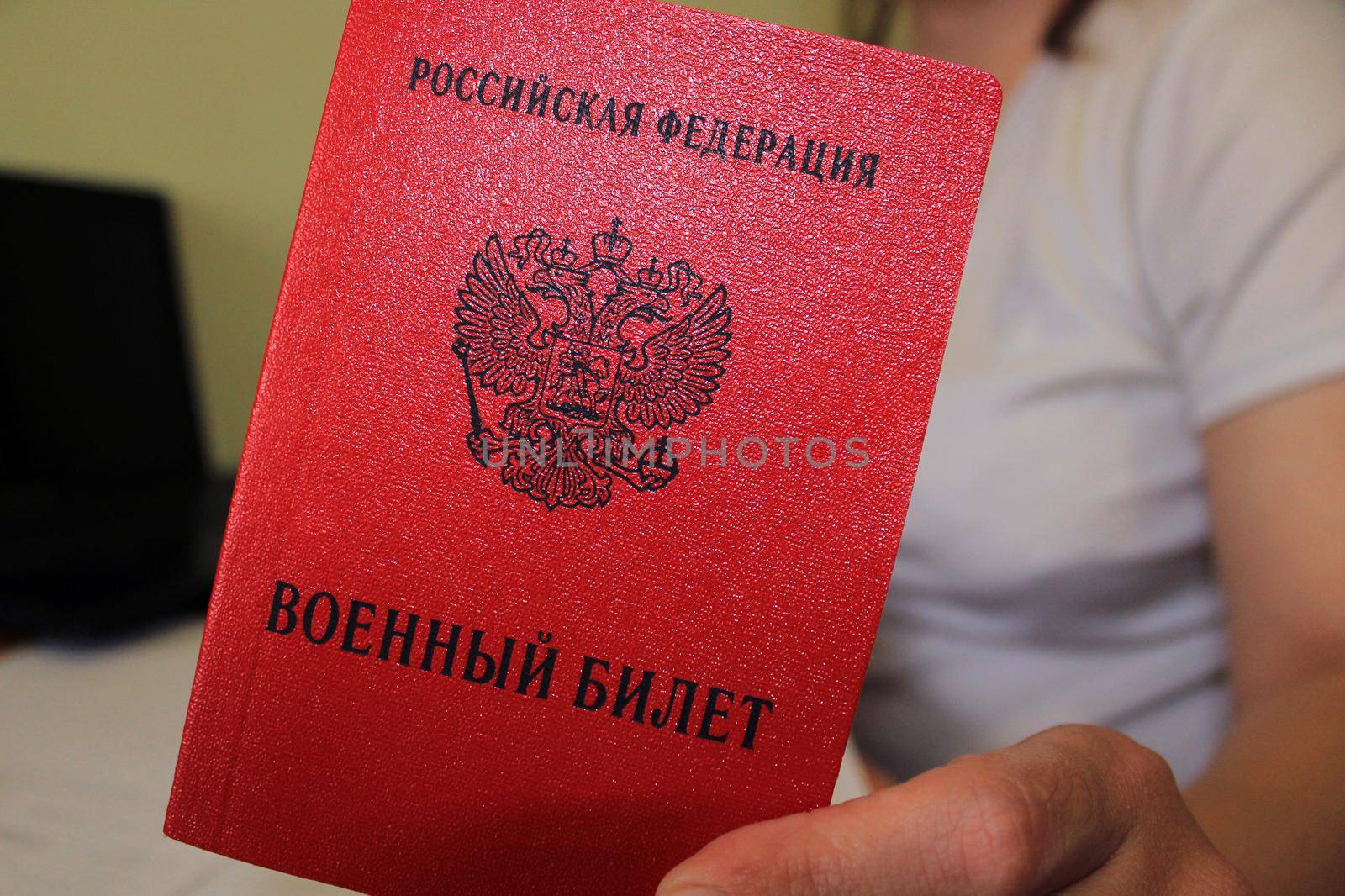 The girl holds in her hand a military ID issued by the Russian Federation. Close-up, blurred background. The concept of mobilization.