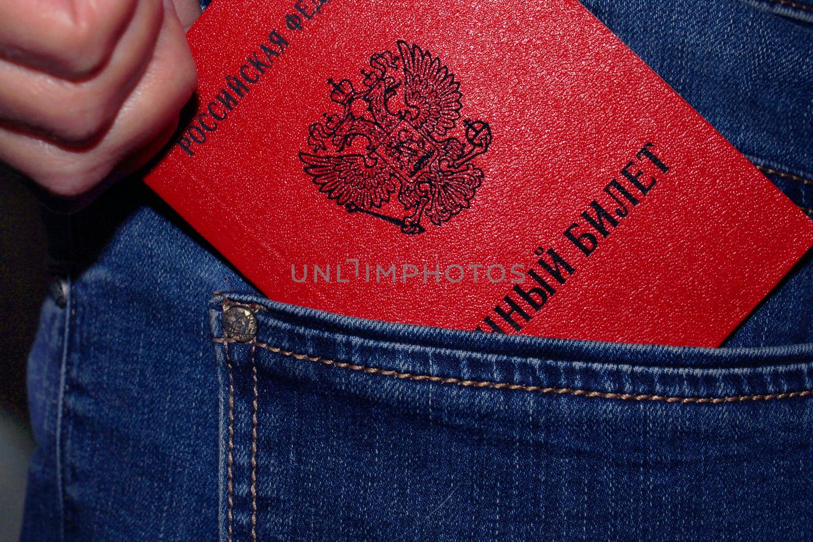 A military ID issued by the Russian Federation is taken out of the back pocket of a jeans close-up. The concept of mobilization.