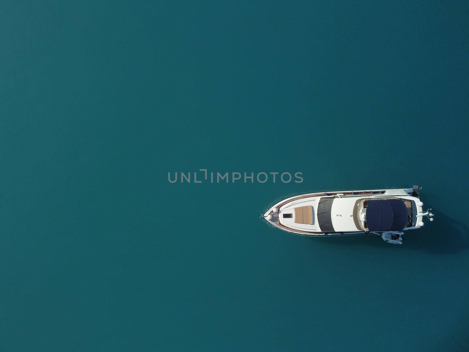 Aerial yacht on calm sea. Luxury cruise trip. View from above of white boat on deep blue water. Aerial top down view of rich yacht sailing sea. Summer journey on luxury ship. by panophotograph