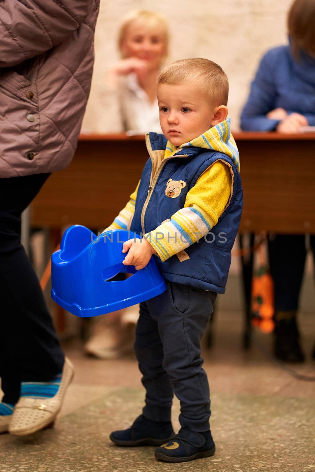 A little boy carries a potty toilet, which he received at the humanitarian center. Dnipro, Ukraine - 04.30.2022