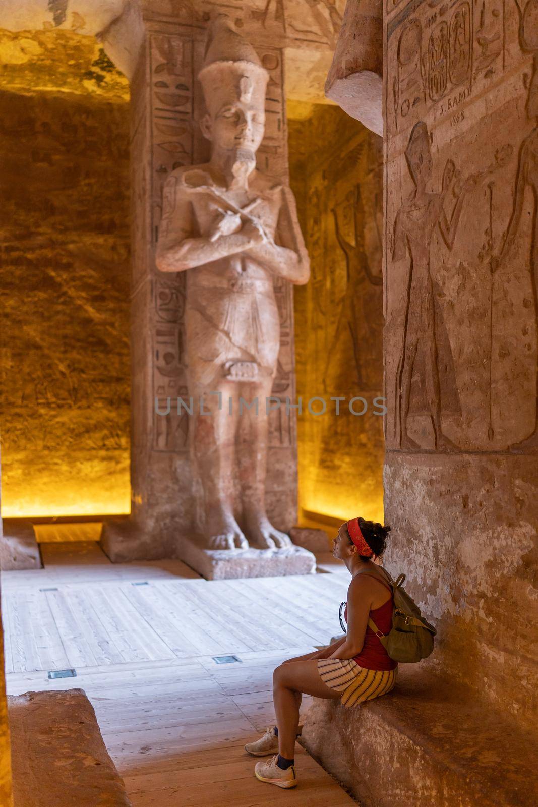 Female tourist seated inside an Egyptian temple and looking at the interior