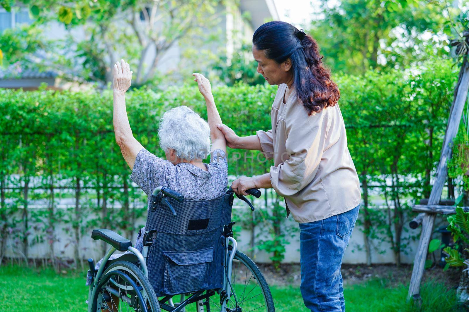 Asian elderly woman disability patient exercise on wheelchair with doctor in park, medical concept.
