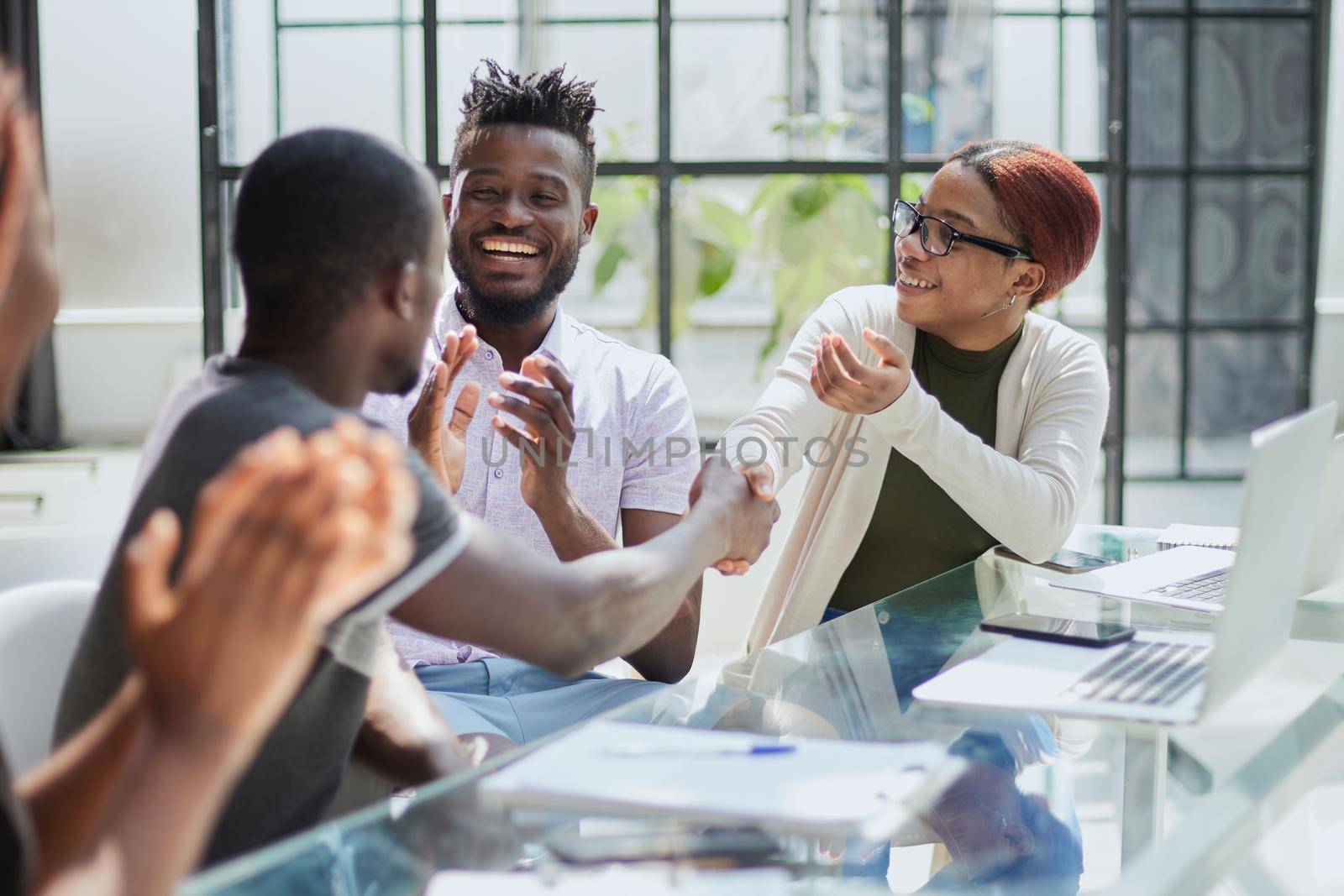 team of young african people in the office shaking hands