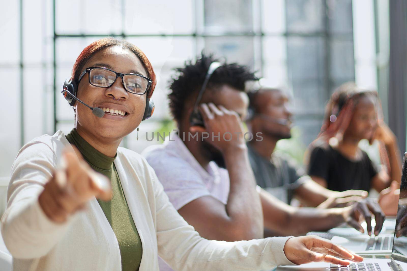 Smiling beautiful African American woman working in call center with diverse team by Prosto