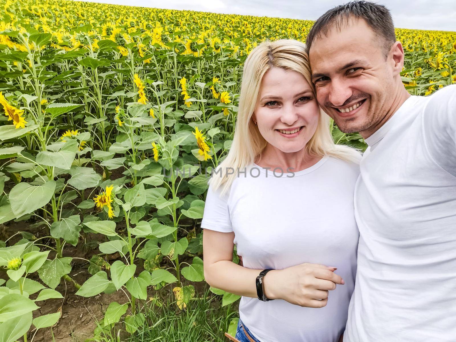 Autumn nature. Young romantic couple walking in sunflower field in sunset by Andelov13