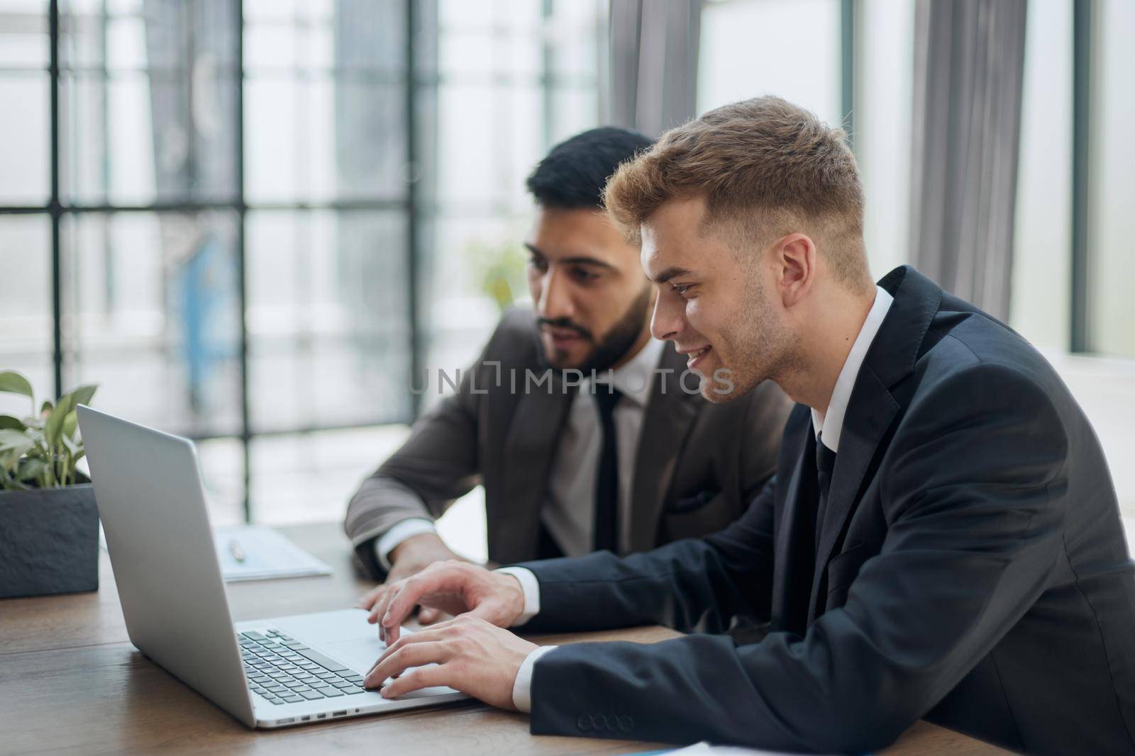 two professional businessmen discussing and using desktop computer in office by Prosto