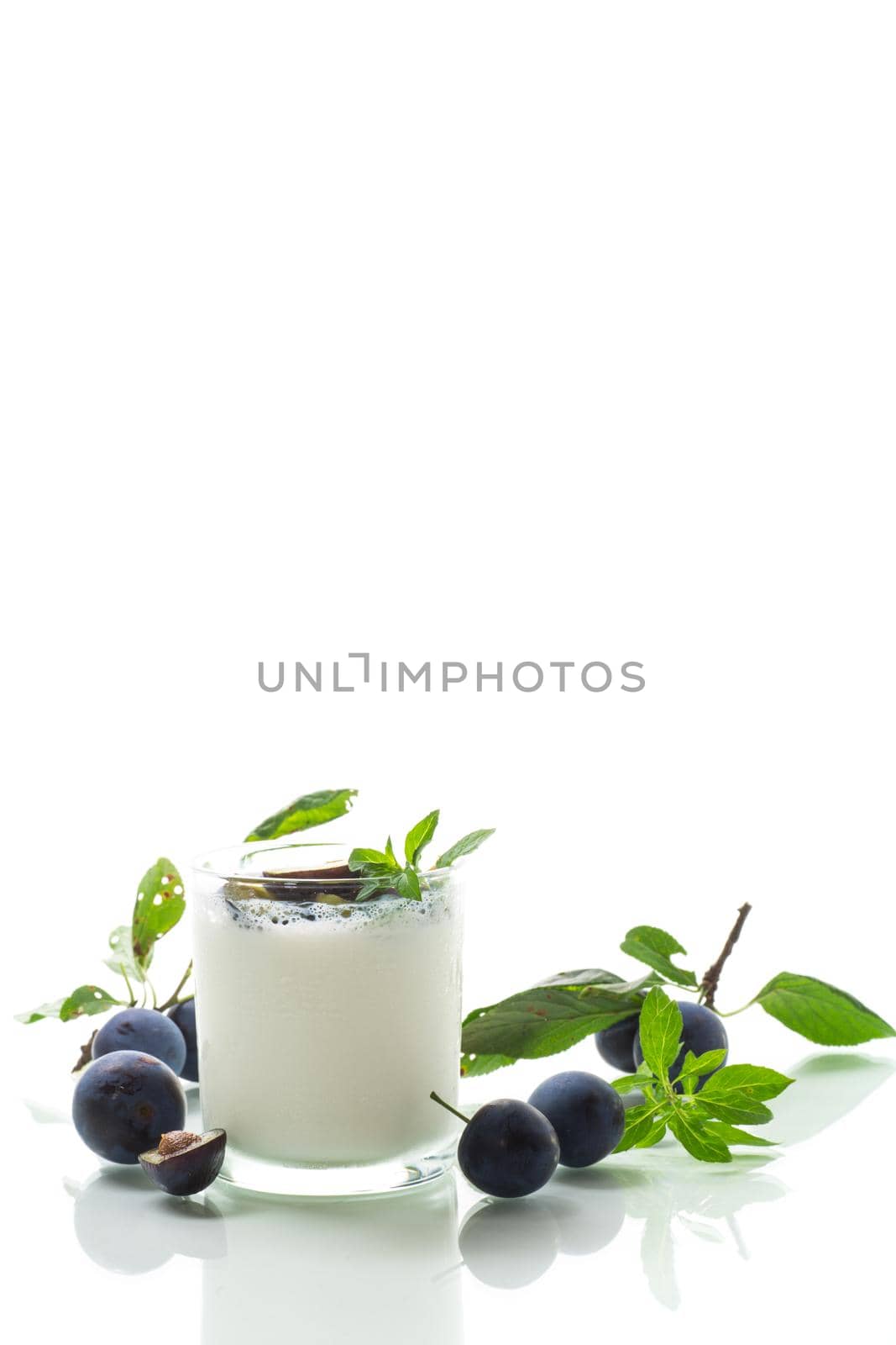 sweet homemade yogurt with fresh plum slices in a glass isolated on white background
