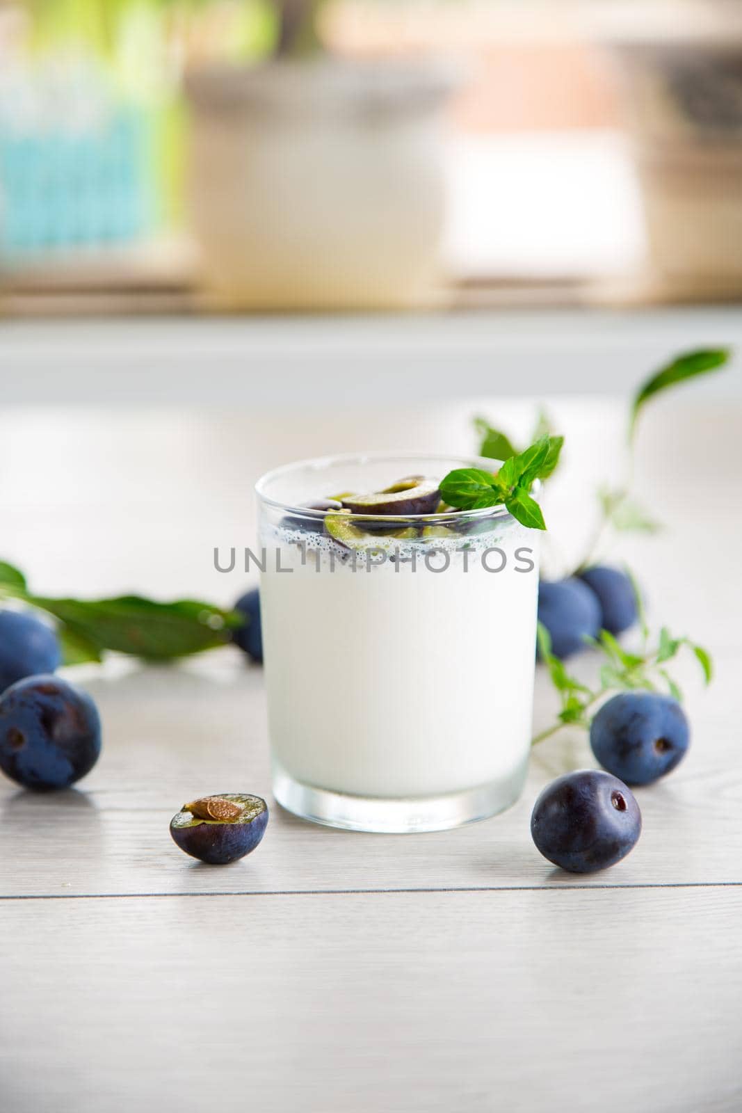 sweet homemade yogurt with fresh plum slices in a glass on a wooden table