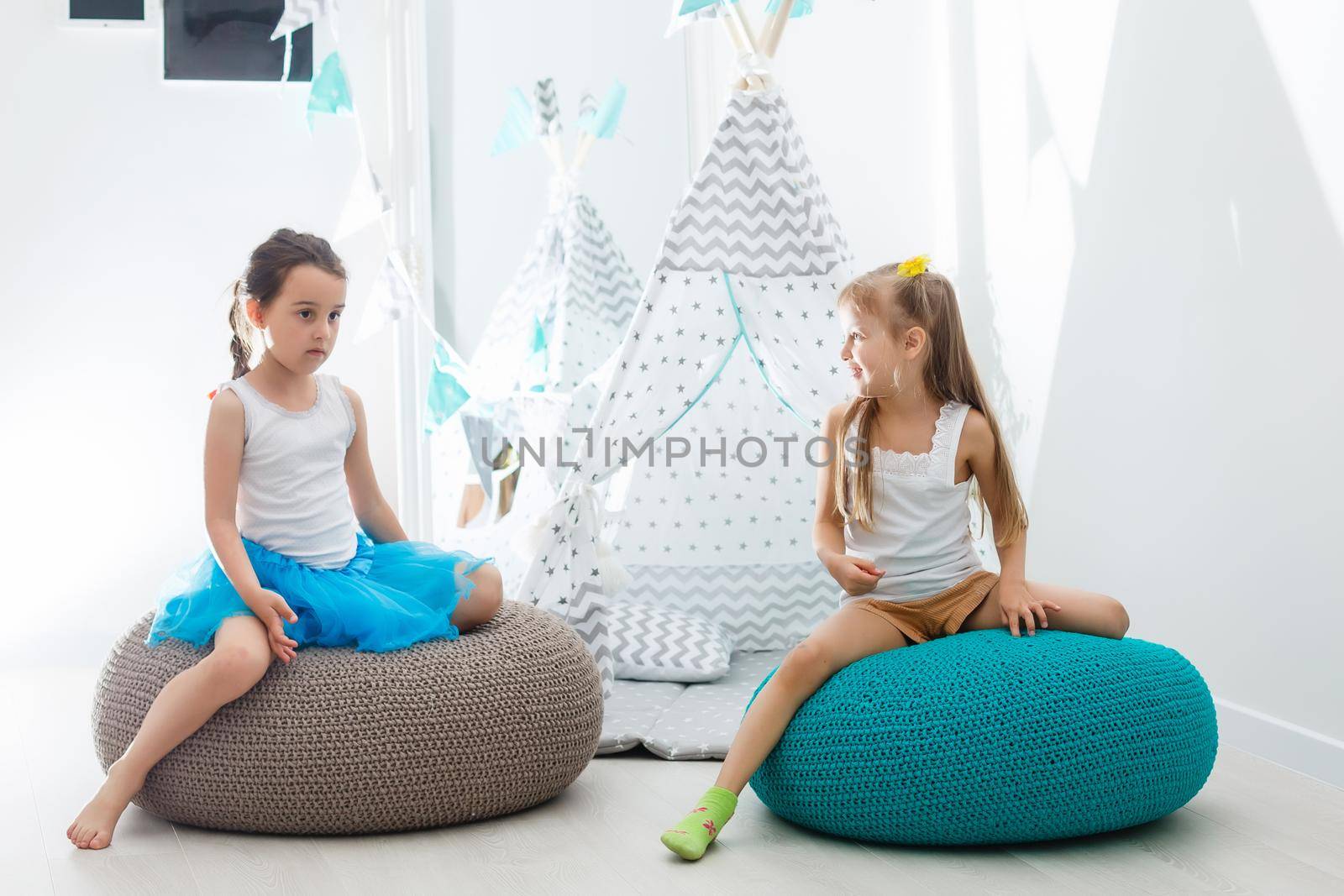 Two happy little girls are smiling while playing in children's room at home