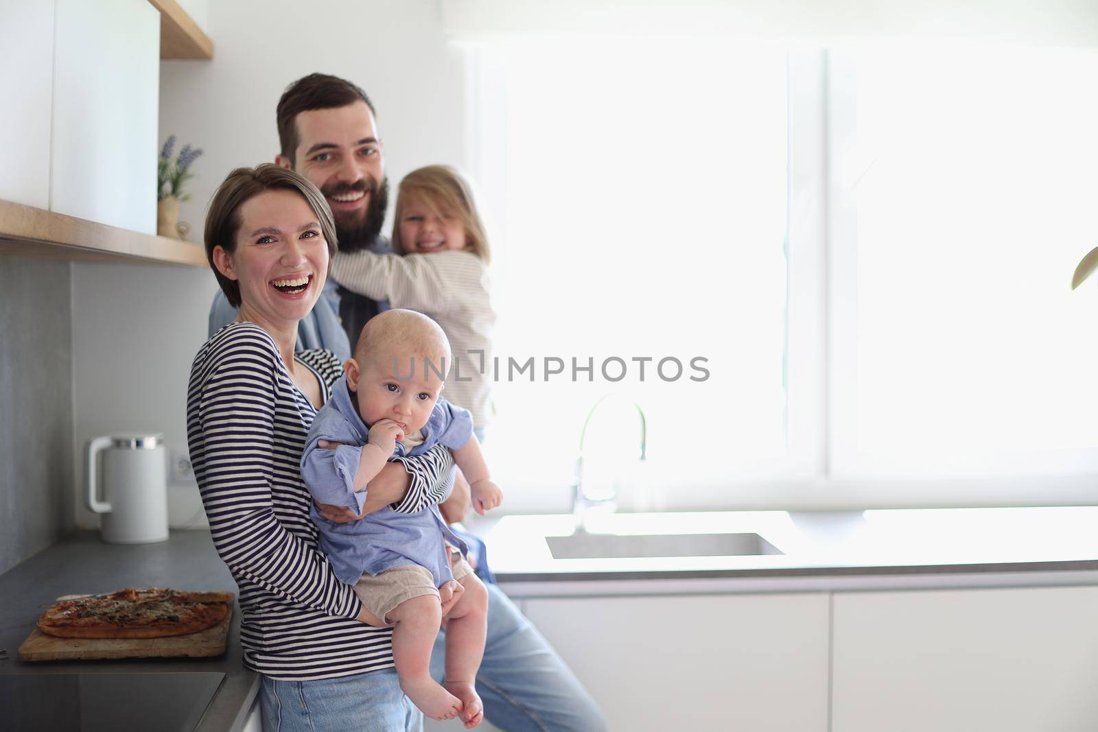 Young family with daughter and son in the kitchen by Prosto