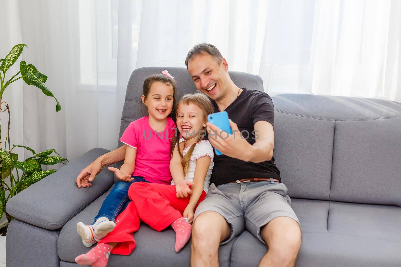 Smile! Young father and his little daughter taking selfie while sitting on floor at home by Andelov13