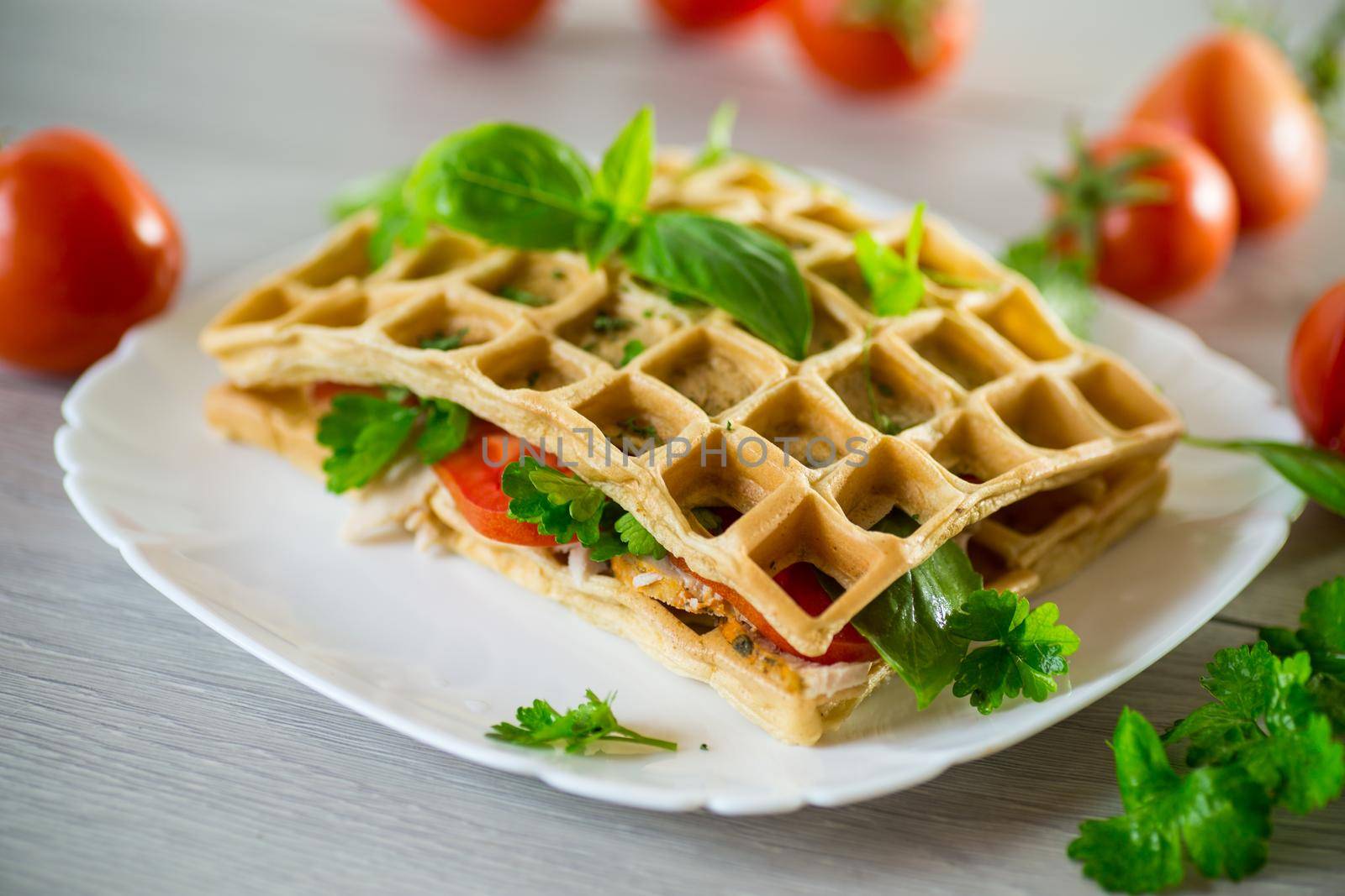 Sandwich of two egg omelettes with bacon and tomatoes inside, waffle shaped.