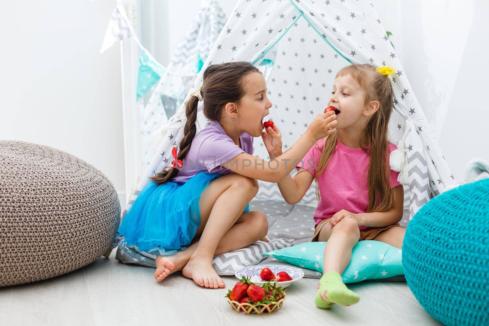 Happy children girl sister eating strawberries