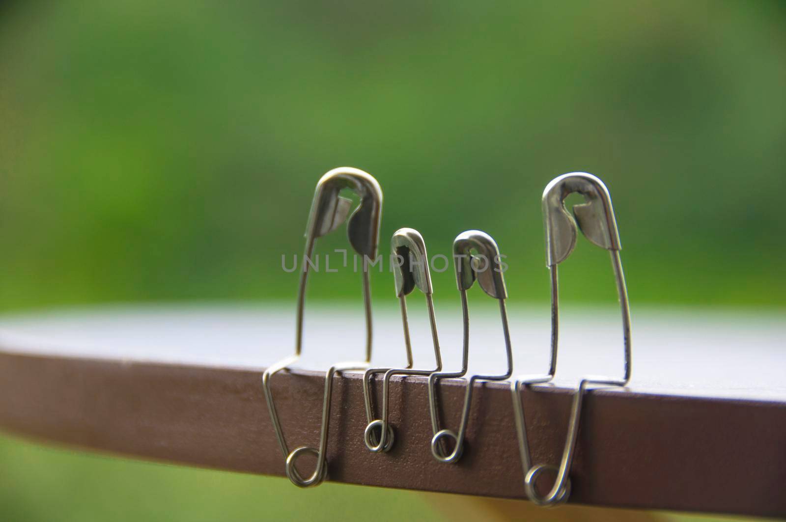 Model safety pin of family sitting on wooden table with blurred nature background. Copy space and family concept.