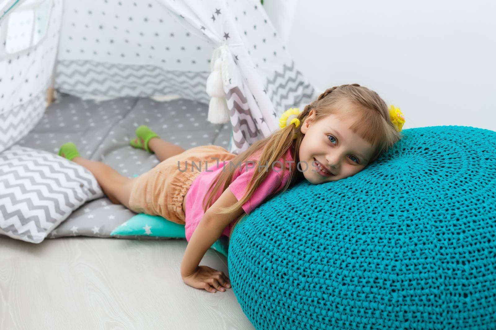 little girl on a children's ottoman near a wigwam