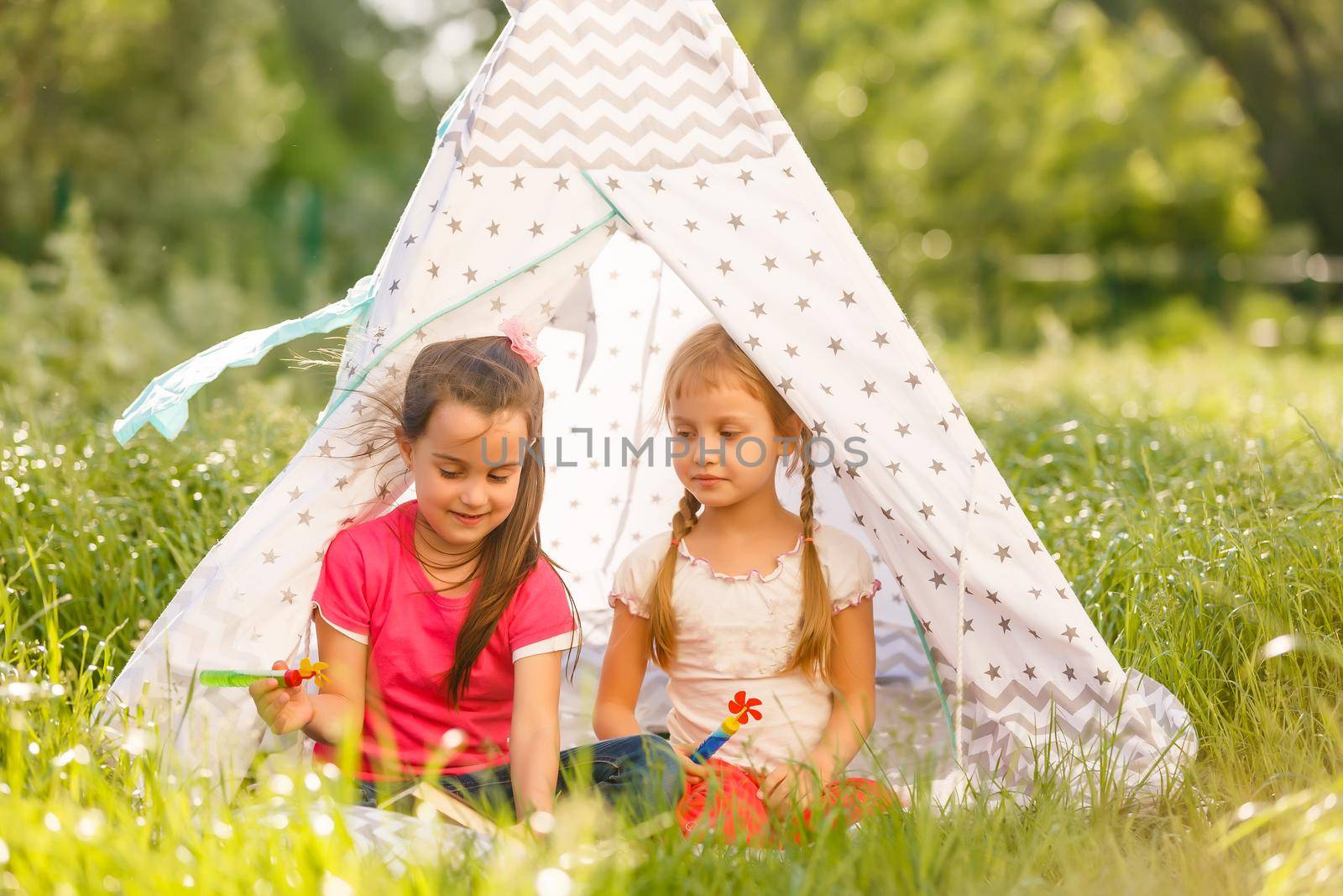 two little girls play near wigwam tent