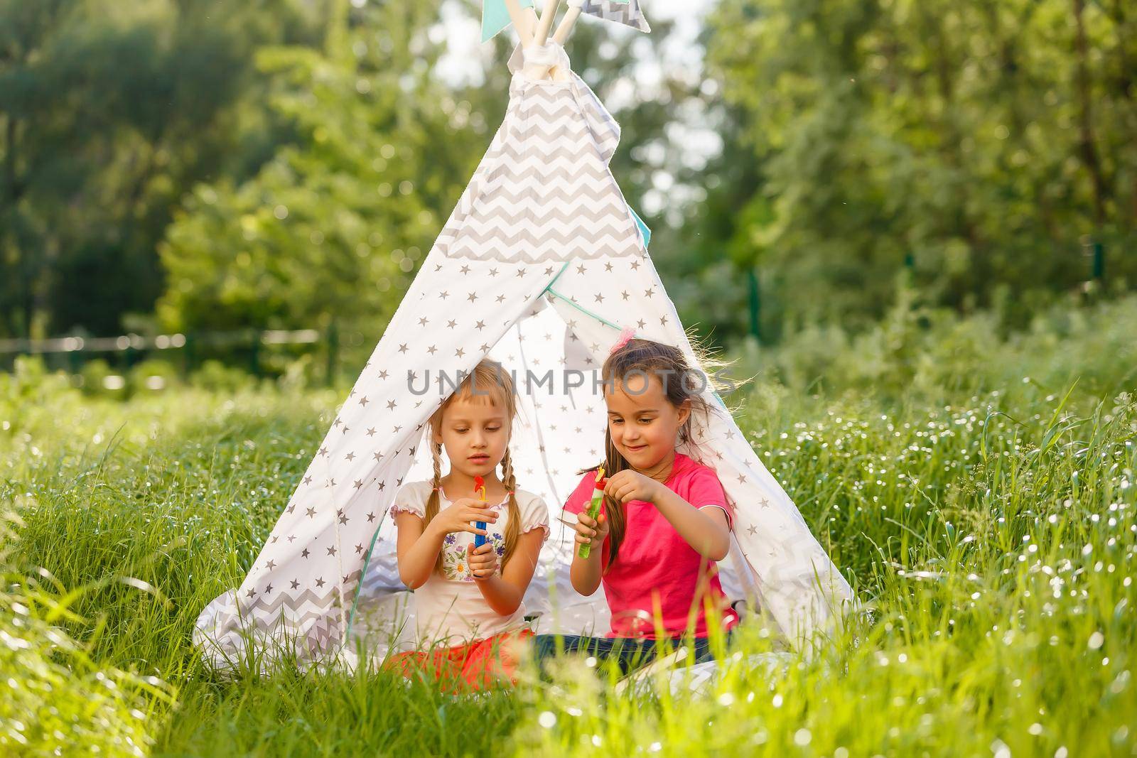 Two little girls are playing in a tent in the park