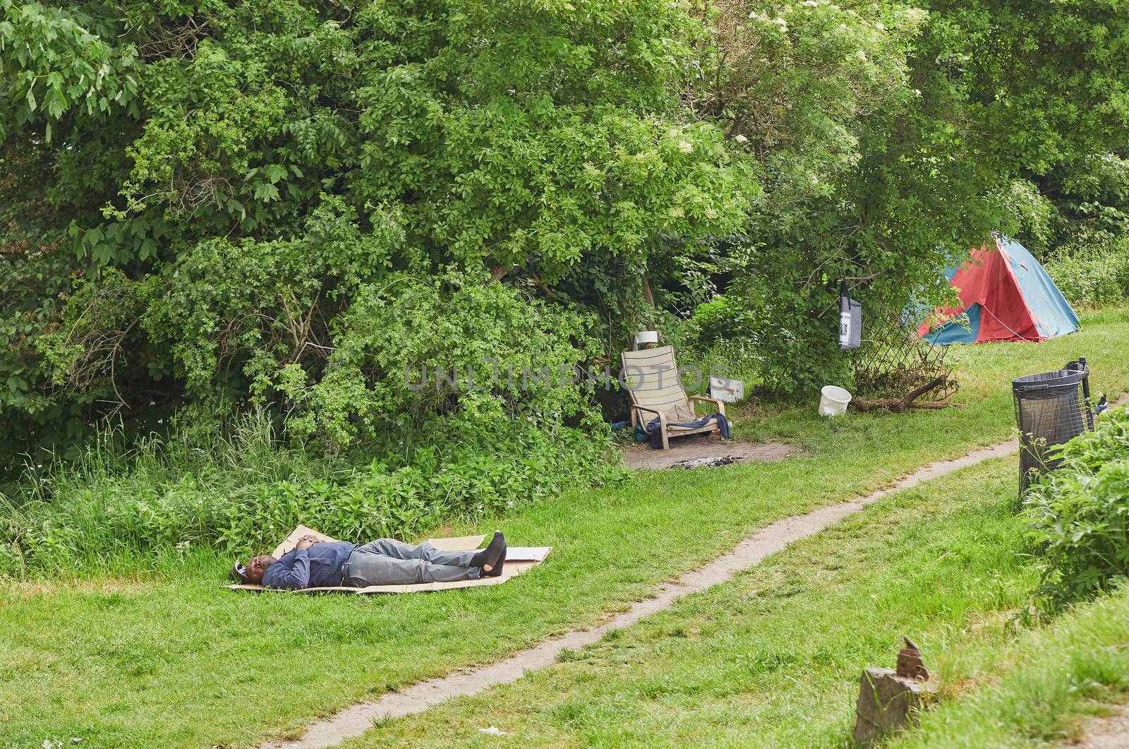 Copenhagen, Denmark, May, 2022: homeless man sleeps on a lawn in the free city of Christiania